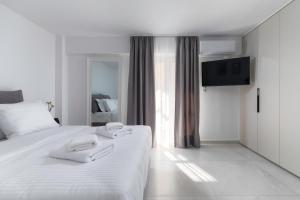a white bedroom with two white towels on a bed at Calliope luxury loft with backyard in Ierápetra