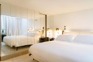 a white bedroom with two beds and a mirror at Villa Marina Capri Hotel & Spa in Capri