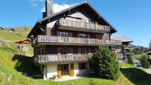 a large house with wooden balconies on a hill at LES RHODOS 1 in Les Crosets