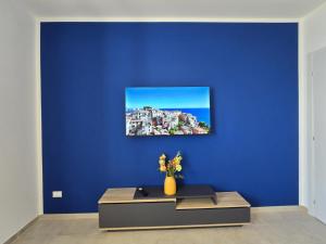 a blue wall with a vase of flowers on a table at Ca' dii Bürsa 2 - HOMY 5 TERRE in Volastra