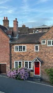 a brick house with a red door and purple flowers at Rondor Cottage in Bridgnorth