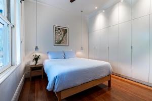 una camera da letto bianca con un letto e una finestra di Villa Catherine - 3BR Lilyfield a Sydney