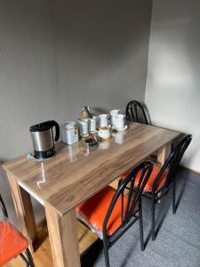 a wooden table with chairs and cups on it at Guest house LEGIANA Kazbegi in Stepantsminda