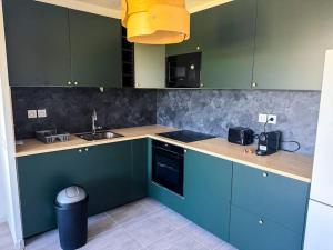 a kitchen with blue and green cabinets and a sink at Somptueux près de Disneyland in Chessy