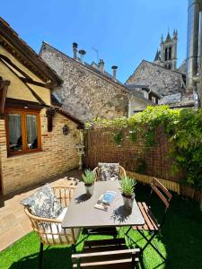 a patio with a table and chairs on the grass at Maison en plein coeur de la cité médiévale de Moret-sur-Loing avec jardin ! in Moret-sur-Loing