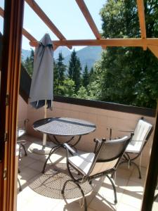 eine Terrasse mit einem Tisch, Stühlen und einem Sonnenschirm in der Unterkunft Garten- & Loggia-Appartement HERRENHAUS in Dellach im Drautal