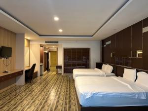 a hotel room with two beds and a desk at โรงแรม อีส จอมเทียน บี in Jomtien Beach