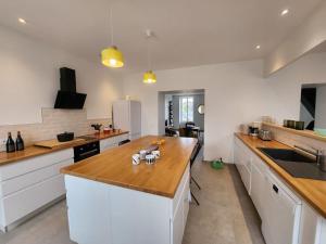 a kitchen with white cabinets and a wooden counter top at La Villa Ausone in Saint-Jean-dʼAngély