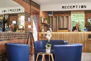 a restaurant with blue chairs and a person on a cell phone at Hôtel Agena in Faches-Thumesnil