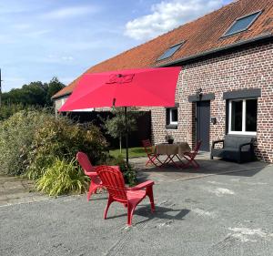 two red chairs and a red umbrella in front of a building at Love Room SPA l'impertinente in Isbergues