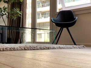 een zwarte stoel in een kamer met een glazen tafel bij Appartement Leon-Rens, op 1 minuut van het strand in Oostende