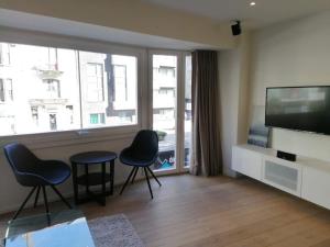 een woonkamer met 2 stoelen en een flatscreen-tv bij Appartement Leon-Rens, op 1 minuut van het strand in Oostende