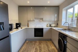 a kitchen with white cabinets and a sink and a dishwasher at Belle Bungalow in Hitchin