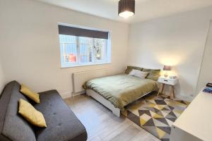 a bedroom with a bed and a couch and a window at Belle Bungalow in Hitchin