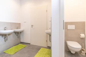 a bathroom with two sinks and a toilet and a yellow rug at Wohnung für 8 Personen in ehemaligem Weingut mit 4 Schlafzimmern in Rommersheim +45 photos