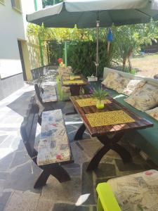 a patio with tables and chairs and an umbrella at Jacky's House in Chernomorets