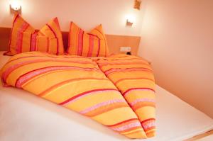 1 cama con edredón de rayas naranja y amarillo en Platterhof, en Avelengo