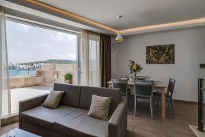 a living room with a couch and a dining room at DuplexPenthouse seafront with hot tub by Homely in St. Paul's Bay
