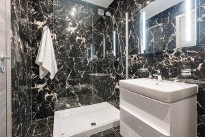 a black tiled bathroom with a toilet and a sink at DuplexPenthouse seafront with hot tub by Homely in St. Paul's Bay +39 photos