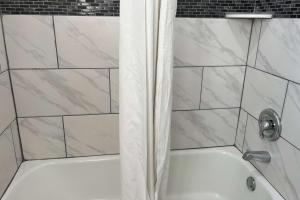 a bath tub with a shower curtain in a bathroom at Travelodge by Wyndham Terre Haute in Terre Haute +15 photos