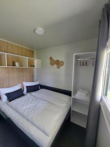 a small bedroom with a bed in a room at SeeRuhe - Mobilheim Grosssteinbach in Grosssteinbach