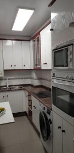 Una cocina con gabinetes blancos y un horno de estufa. en Apartamento Avenida Constitución, en Boiro