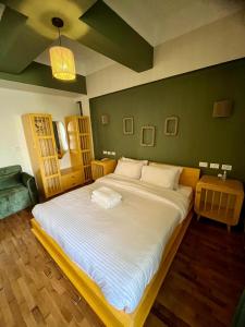 a large bed in a room with a green wall at Town View Studios in Cairo