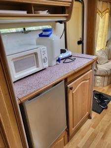 an rv kitchen with a microwave and a refrigerator at Pirttiniemen Lomakylä in Muurasjärvi +19 photos