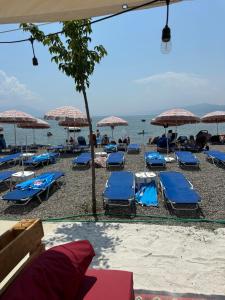 a beach with blue chairs and umbrellas and the ocean at M&D Apartment in Struga
