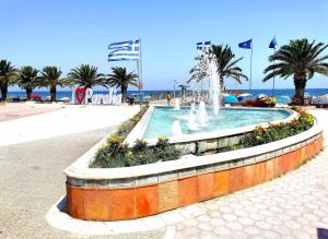 a fountain on the beach with palm trees and the ocean at Premium Studio DANAI 14 Paralia Beach in Paralia Katerinis