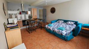 ein Wohnzimmer mit einer blauen Couch und einer Küche in der Unterkunft Maison de plain-pied avec un grand jardin in Malicorne-sur-Sarthe + 16 Fotos