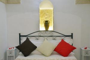 Schlafzimmer mit einem Bett mit roten und schwarzen Kissen in der Unterkunft Le Nicchie Ostuni in Ostuni