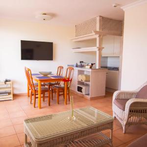 a living room with a table and chairs and a kitchen at Apartment Hotel TABOGA in Playa del Ingles