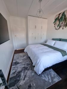 Un dormitorio con una gran cama blanca y un televisor. en Troon Harmony - Room 2, en Durban