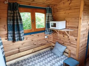 a room in a log cabin with a microwave at Roulottes - Les lits de berger in Saint-Front