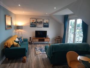 a living room with a green couch and a tv at Idyllic Waterside Penthouse in Callander