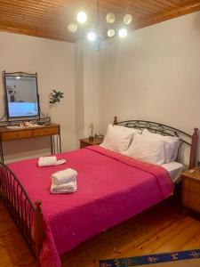 a bedroom with a bed with a pink blanket and a tv at Petra Maisonettes in Kariá