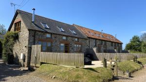 ein Steinhaus mit einem Zaun davor in der Unterkunft East Trayne Holiday Cottages in South Molton