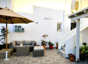 a patio with a couch and an umbrella at Dolphin Rooms in Antiparos