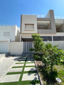 une maison blanche avec des arbres devant dans l'établissement The Private chalet للعائلات فقط, à Al Khiran 12 autres photos