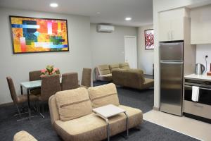 a living room with a couch and chairs and a kitchen at Ratsun Nadi Airport Apartment Hotel in Nadi