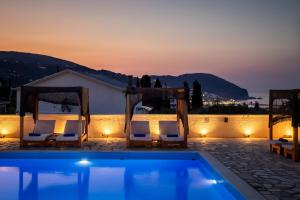 a swimming pool with two chairs and a tent at Skopelos Holidays Hotel & Spa in Skopelos Town