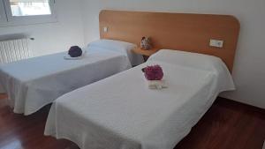 two beds with white sheets and purple flowers on them at Hotel Victorino in Silleda +7 photos