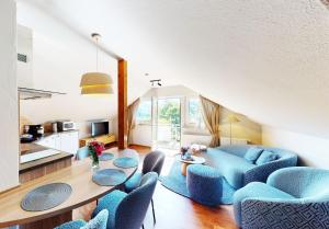 Una sala de estar con un sofá azul y sillas. en Edelweiss Appartements 'ETTELSBERG' deluxe inkl Wellness-Spa und MeineCardPlus, en Willingen