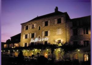 a large brick building with a neon sign on it at Logis Hôtels - Hôtel et Restaurant Le Lion d'Or in Gramat