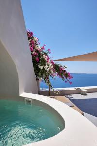 a jacuzzi tub with flowers on the side of a building at Elegant Santorini House 3 Bedroom Villa Caldera View-Outdoor Hot Tub Oia in Thólos