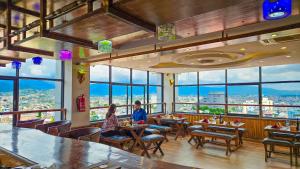 two people sitting at tables in a restaurant with a view at Drishya Hotel in Kathmandu