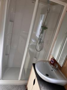 a bathroom with a shower and a white sink at Allhallows getaway in Rochester