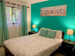 a bedroom with a bed with green walls and two lamps at Cocomarindo Breeze Condo And Amazing Pool in Coco +26 photos