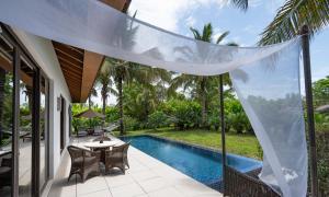 an outdoor patio with a table and chairs next to a pool at The Residence Zanzibar in Kizimkazi